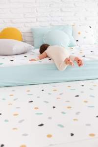 Colección huellas mint, alfombra vinílica, saco nórdico, cojines con borlas mint y mostaza