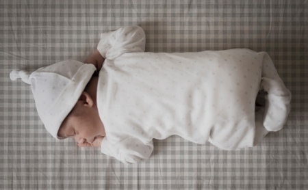 Bebé durmiendo sobre sábana mini cuna y capazo cuadro vichy gris. Tejido 100% algodón orgánico. Estrellita la Valiente.