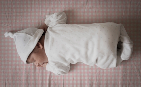 Bebé durmiendo sobre sábana mini cuna y capazo cuadro vichy rosa. Tejido 100% algodón orgánico. Estrellita la Valiente.
