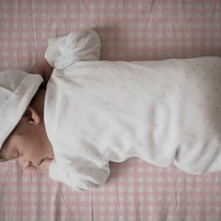 Bebé durmiendo sobre sábana mini cuna y capazo cuadro vichy rosa. Tejido 100% algodón orgánico. Estrellita la Valiente.
