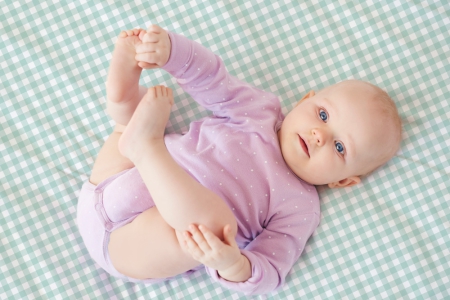 Bebé tocándose un pie sobre sábana mini cuna y capazo cuadro vichy mint. Tejido 100% algodón orgánico. Estrellita la Valiente.