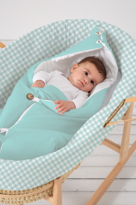 Vestidura para capazo vichy mint con bebé. Vestidura de moisés de bebé de la tienda online de textil hogar, accesorios y decoración infantil con confección propia en la Comunidad Valenciana. Diseños propios con tejidos 100% algodón orgánico, hechos en España, sostenibles y ecológicos.