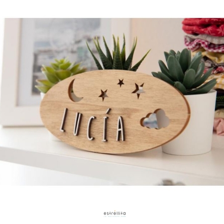 Detalle sobre ambiente de una placa ovalada adhesiva personalizada de Estrellita la Valiente. Placa de madera con el nombre de Lucía y troquelado de estrellas, luna y nube.