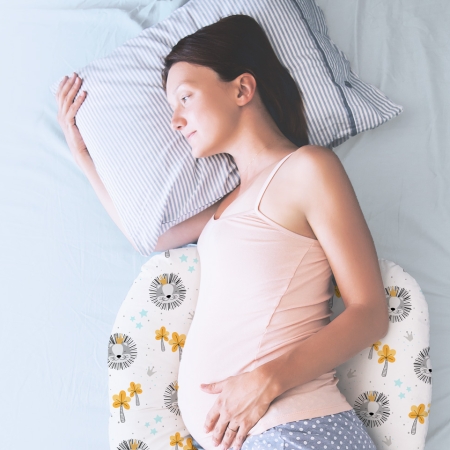 Mujer embarazada tumbada en la cama de lado sobre un cojín de lactancia Rey de la Selva Estrellita la Valiente.