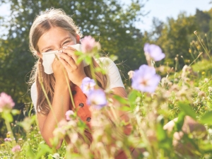 Imagen de una niña tapándose la nariz porque le da alergia el polen de las flores