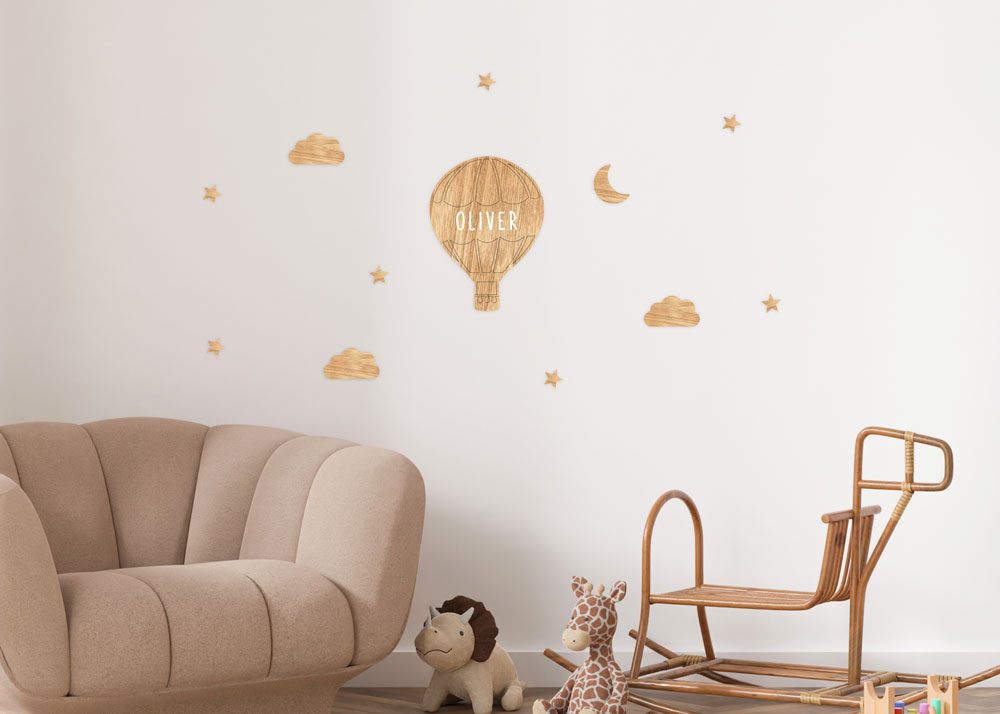 Imagen de la decoración de pared de madera personalizable Globo de Estrellita la Valiente. Imagen de una habitación infantil con el vinilo personalizable de madera de bosques sostenibles con estrellas, nubes, luna y un globo.