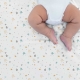 Bebé tumbado boca arriba sobre sábana noche estrellada mostaza Estrellita la Valiente. Bebé boca arriba sobre uno de los juegos de minicuna y capazo Noche estrellada mostaza.
