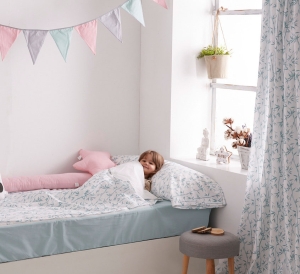 Detalle saco nórdico con cremallera habitación infantil. Niña dentro de un saco nórdico con estampación de ramas de bambú.
