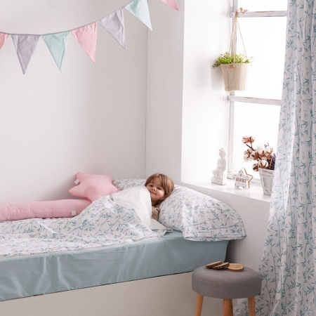 Detalle saco nórdico con cremallera habitación infantil. Niña dentro de un saco nórdico con estampación de ramas de bambú.