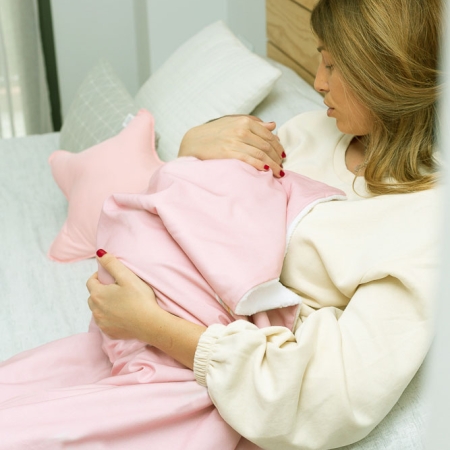 Manta polar rosa. Mamá con un bebé en brazos tapado con una manta rosa