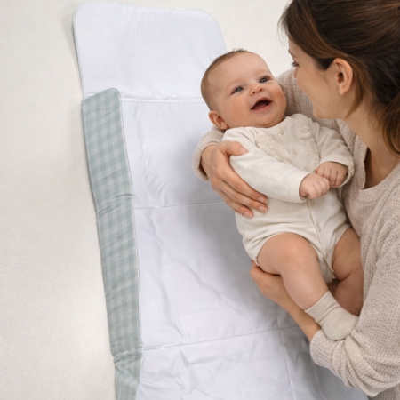 Cambiador plegable cuadro vichy mint Estrellita la Valiente. Mamá intentando colocar a un bebé sobre el cambiador plegable