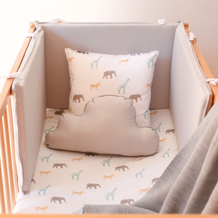 Conjunto funda de protector gris y cojines. Chichonera de color gris en una cuna. Cojín animales de la sábana y cojín nube gris
