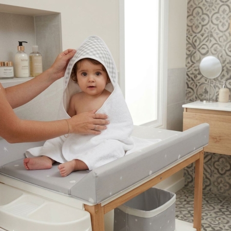 Bebé con capa de baño cuadro vichy gris sobre bañera. Capa de baño con estampado cuadro vichy gris