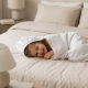 Niña con capa de baño Bambú tumbada sobre cama. Capa de baño o toalla con capucha con estampado Bambú