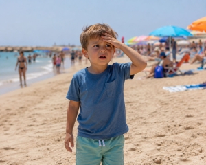 Niño perdido en la playa con la mano en la cabeza y asustado