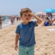 Niño perdido en la playa con la mano en la cabeza y asustado